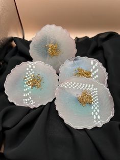 three white flowers with gold centers sitting on a black cloth