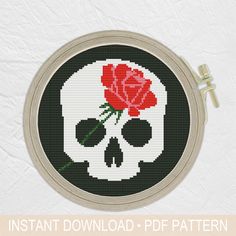 a cross stitch skull with a red rose on it