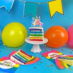 a birthday cake on a table with balloons and confetti around it, in front of a blue background