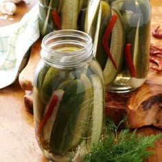 jars filled with pickles sitting on top of a table next to other food items