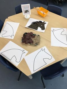 paper cut out of horses sitting on top of a wooden table with chairs around it