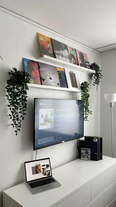 a flat screen tv sitting on top of a white dresser next to a laptop computer