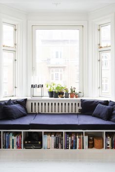 a blue couch sitting next to a window filled with lots of books on top of a book shelf