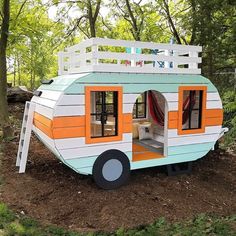 a tiny house made out of wood and painted orange, white and blue with a ladder on the roof