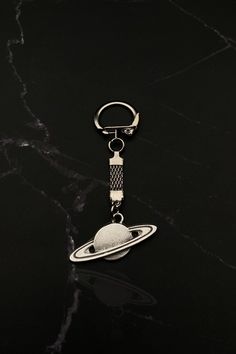 a metal keychain with an object hanging from it's side on a marble surface