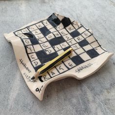 a piece of art that looks like a crossword puzzle with a pen on it