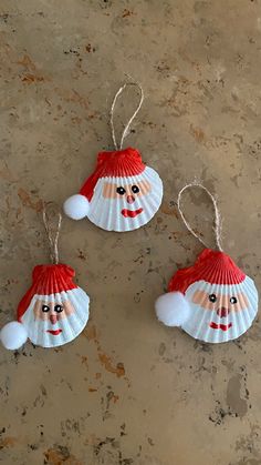 three christmas ornaments with santa claus on them, hanging from strings and sitting on a stone surface