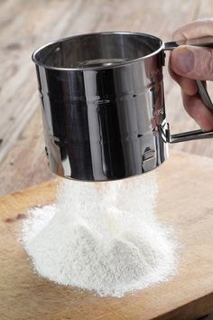 a person pouring sugar into a measuring cup