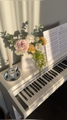 a white piano with flowers and music sheet