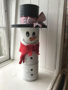 a snowman made out of tin cans sitting on top of a window sill