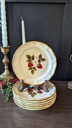 a stack of plates sitting on top of a wooden table next to a lit candle