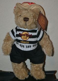 a brown teddy bear wearing a black and white shirt with a hat on it's head