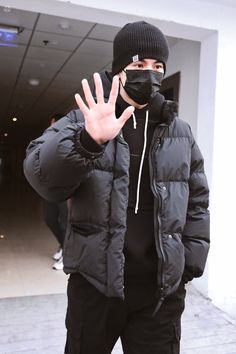 a man wearing a black mask and jacket making the vulcan hand sign with his right hand