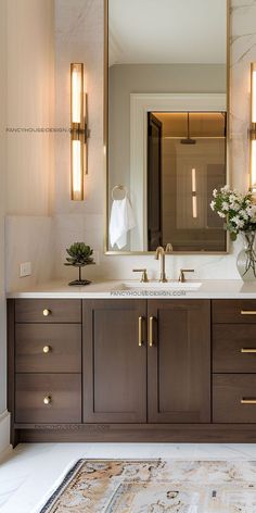 a bathroom vanity with two sinks and lights on the wall above it, along with a rug