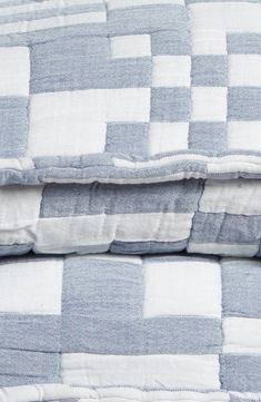 two blue and white checkered bedspreads stacked on top of each other