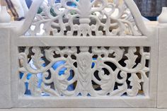 an intricately designed white marble bench with decorative carvings on the top and bottom part