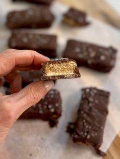 a hand holding a piece of chocolate with gold flecks on it and other pieces in the background