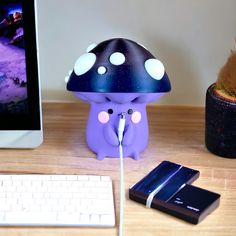 a purple mushroom lamp sitting on top of a desk next to a keyboard and mouse