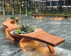 a wooden bench sitting on top of a stone floor next to a planter filled with flowers