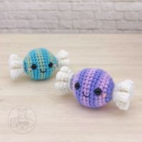 two small crocheted fish sitting next to each other on top of a wooden table