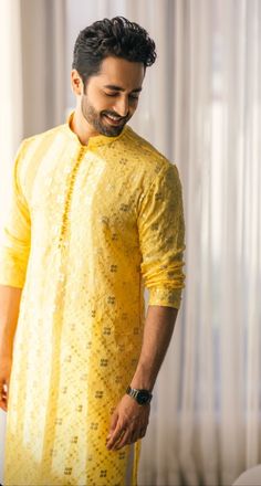 a man in a yellow outfit standing next to a window and smiling at the camera