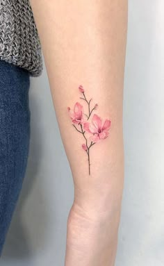 a small pink flower tattoo on the left inner arm and leg, with watercolor style flowers