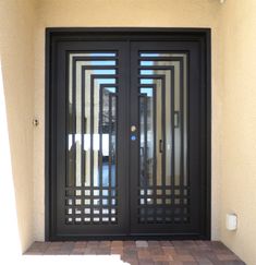 a black double door with metal bars on the side and brick walkway in front of it