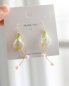 a pair of earrings with flowers and pearls hanging from it's earwires