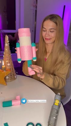 a woman is sitting at a table with some crafting supplies on top of it