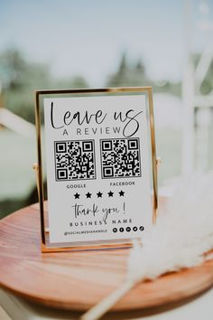 a close up of a sign on a wooden table with a white feather in front of it