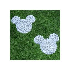 two mickey mouse heads made out of pebbles sitting on the grass in front of each other