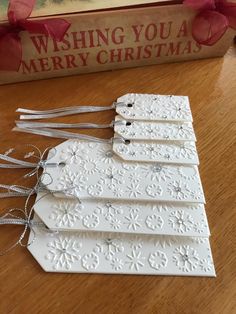 four white tags are sitting on a table next to a book with red ribbon and bow