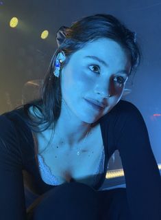 a woman sitting on top of a chair in front of a stage with lights behind her