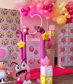 a pink room with balloons and decorations on the walls, including an inflatable mario kart figure