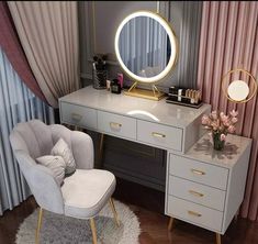 a desk with a chair, mirror and flowers on it in front of a curtained window