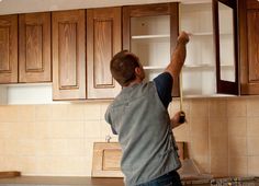 a man is working on cabinets in the kitchen