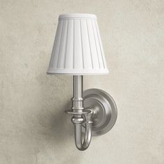 a white lamp mounted on a wall next to a light fixture with a white shade