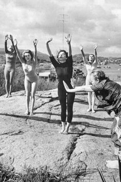 five women standing on top of a rock with their arms in the air and one woman holding her leg up