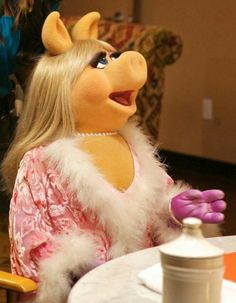 the miss piggy doll is sitting at a table