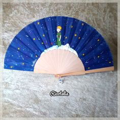 a blue fan with a little boy on it sitting on top of a white carpet