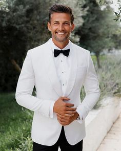 a man in a white tuxedo smiles at the camera