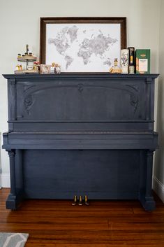 an old piano is sitting on the floor in front of a wall with a map