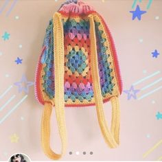 a crocheted backpack hanging on a wall with stars around it and a photo frame