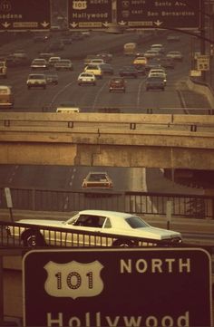 a highway with cars driving on it and an over pass sign in the foreground