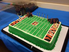 a football field birthday cake with candles on the top and green frosting, sitting on a blue tablecloth