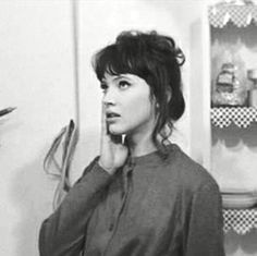 black and white photograph of a woman in the kitchen talking on her cell phone while holding a pen