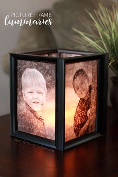 an illuminated cube with two pictures of children in it on a table next to a potted plant