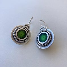 These Boho Silver Dangle Earrings feature a unique round tribal design with vibrant green enamel at the center. The intricate pattern on each earring is complemented by a detailed ornate border, adding a touch of elegance and allure. The hooks ensure a secure and comfortable fit, making these earrings perfect for any occasion. I've crafted these earrings from silver-plated Zamac, a material known for its durability and resistance to tarnish. The green enamel is carefully selected for its vibrant color and smooth finish. Each earring measures 3.8 cm in length and 2.2 cm in width (approximately 1.5 inches by 0.87 inches). Every pair is meticulously handmade by me, ensuring a unique and personal touch in each piece. These earrings can be a perfect gift for your loved ones, offering both style Ornate Border, Bohemian Handmade, Silver Dangle Earrings, Green Enamel, Vibrant Green, Ethnic Jewelry, Silver Earrings Dangle, Jewelry For Women, Jewelry Earrings Dangle