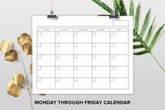 the monday through friday calendar on a clipboard next to some leaves and a plant