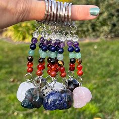 a woman's hand holding several bracelets with different colored beads and charms on them